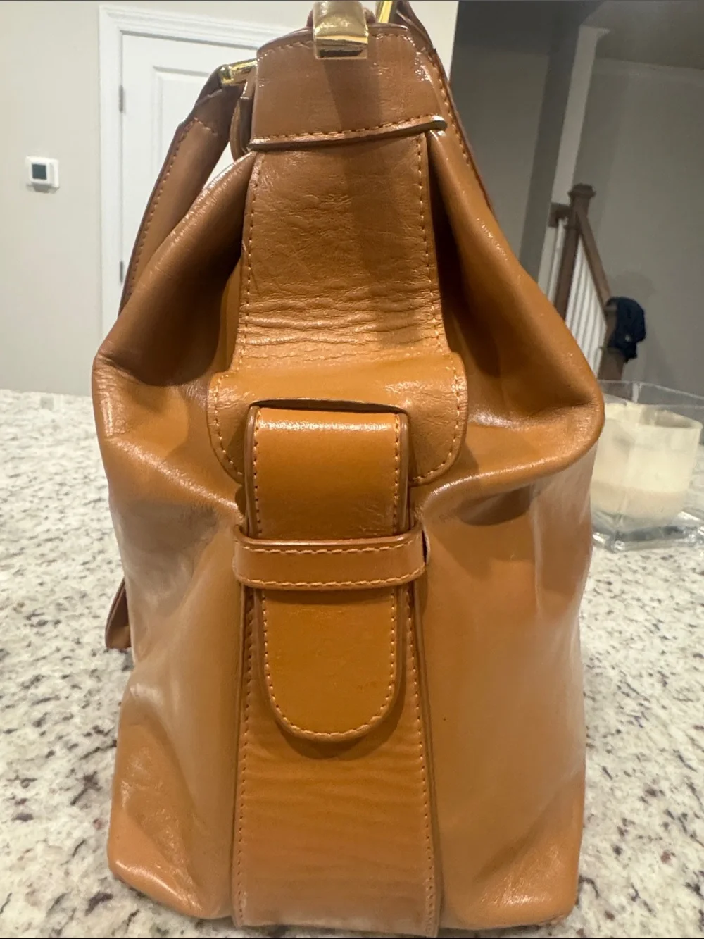 The Find Classic Tan Leather Weekender Travel Bag with Gold Hardware Buckle.